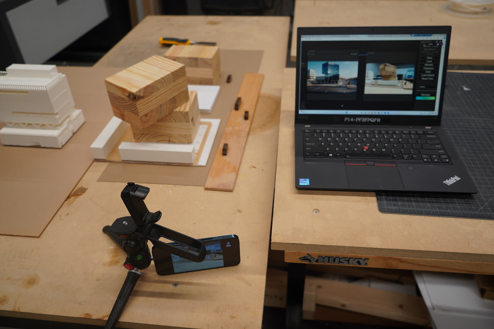 Workshop bench with chipboard model, camera on a tripod, and a laptop running ComfyUI